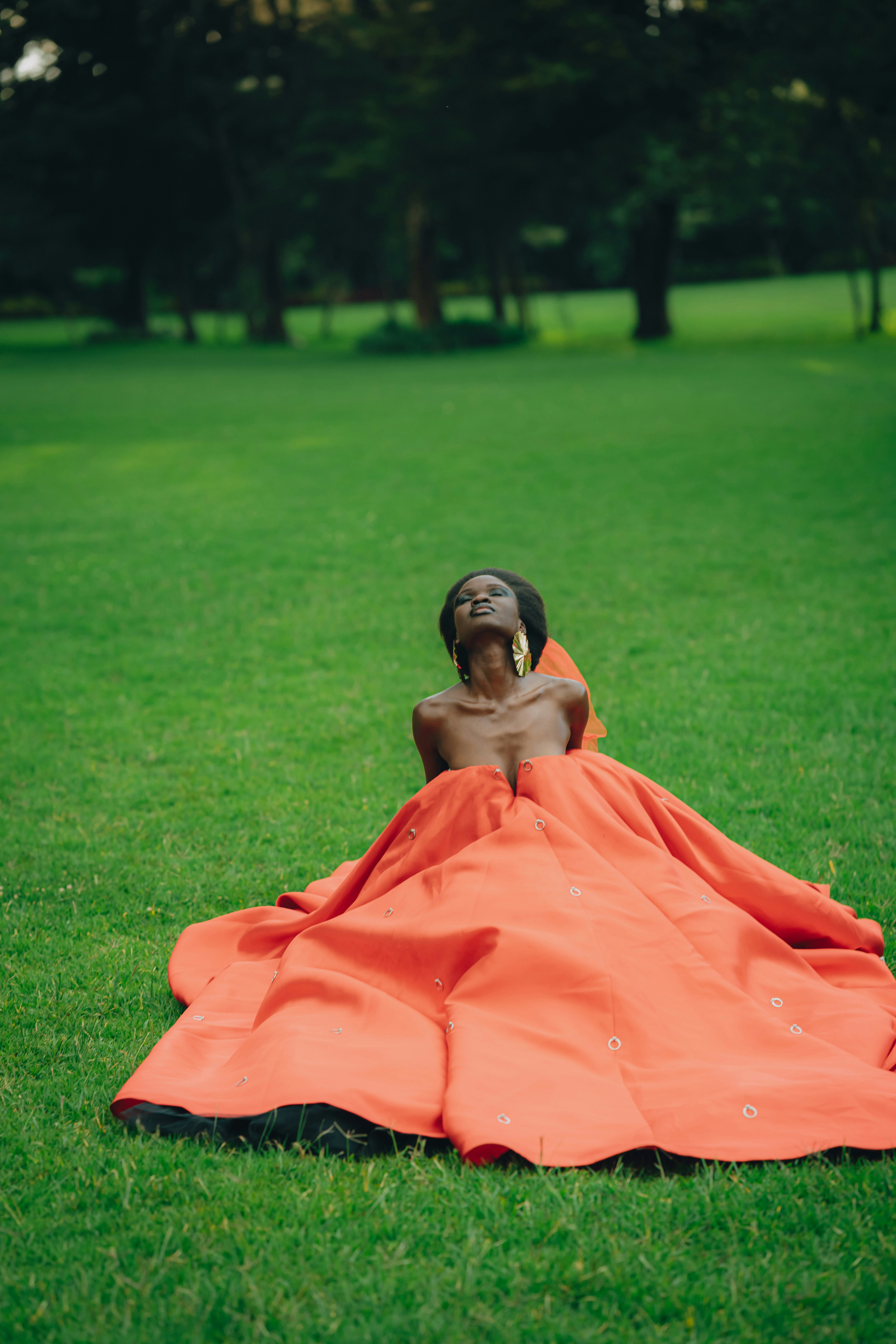 A woman in a vibrant orange dress poses on grass. photo  Free Green Image  on Unsplash
