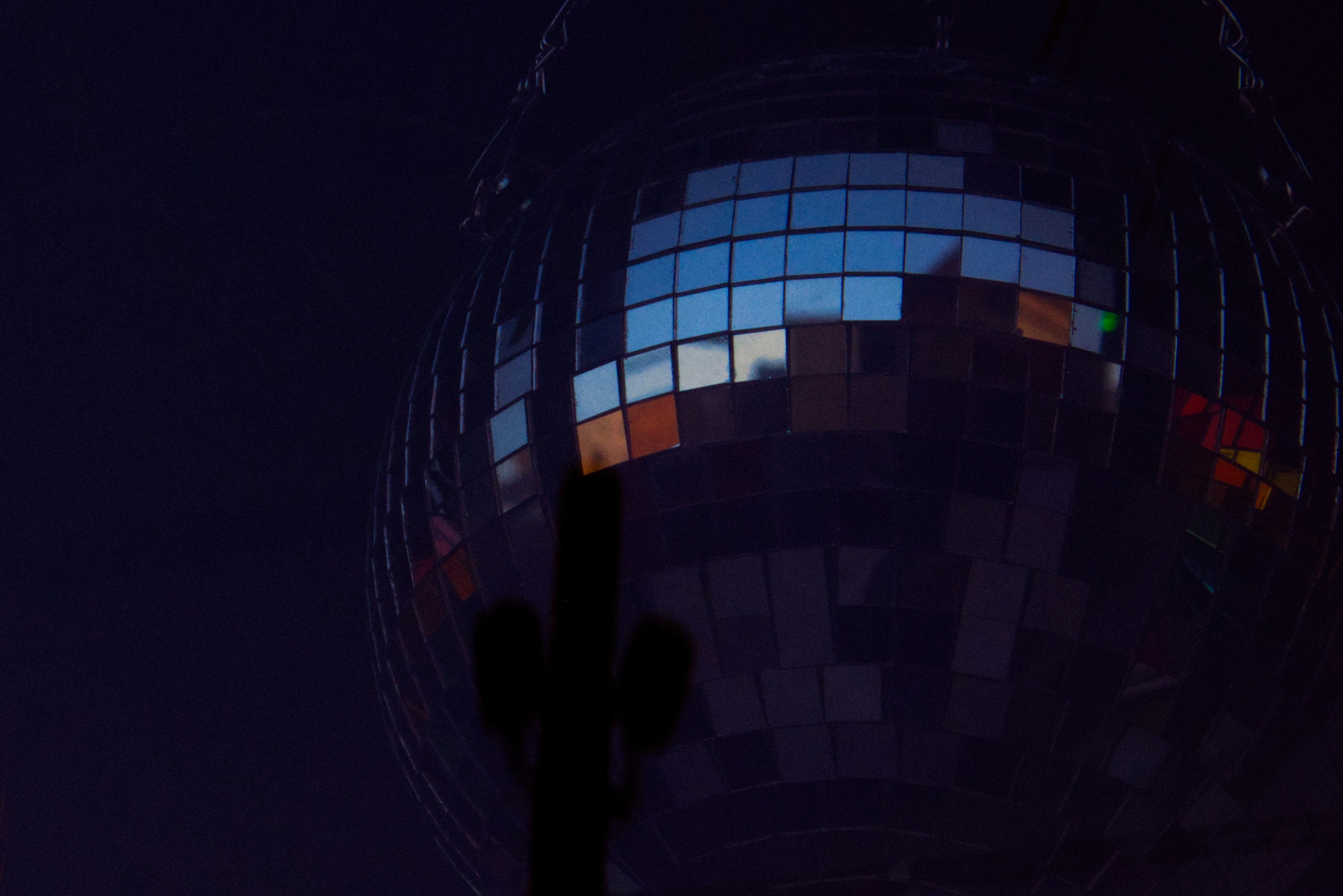 A disco ball reflects light in the dark.