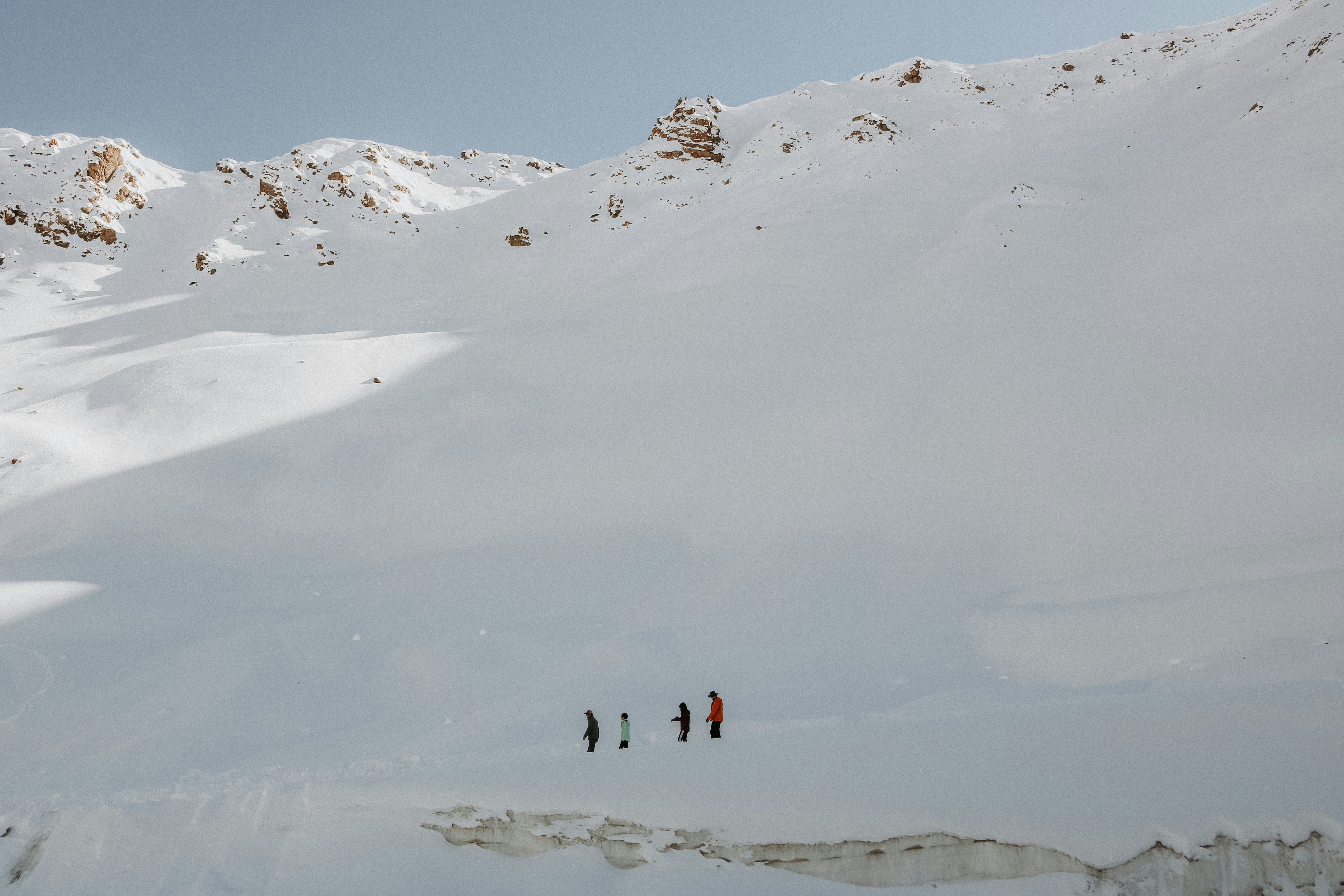 Die Leute fahren mit Skiern einen verschneiten Berg hinunter.