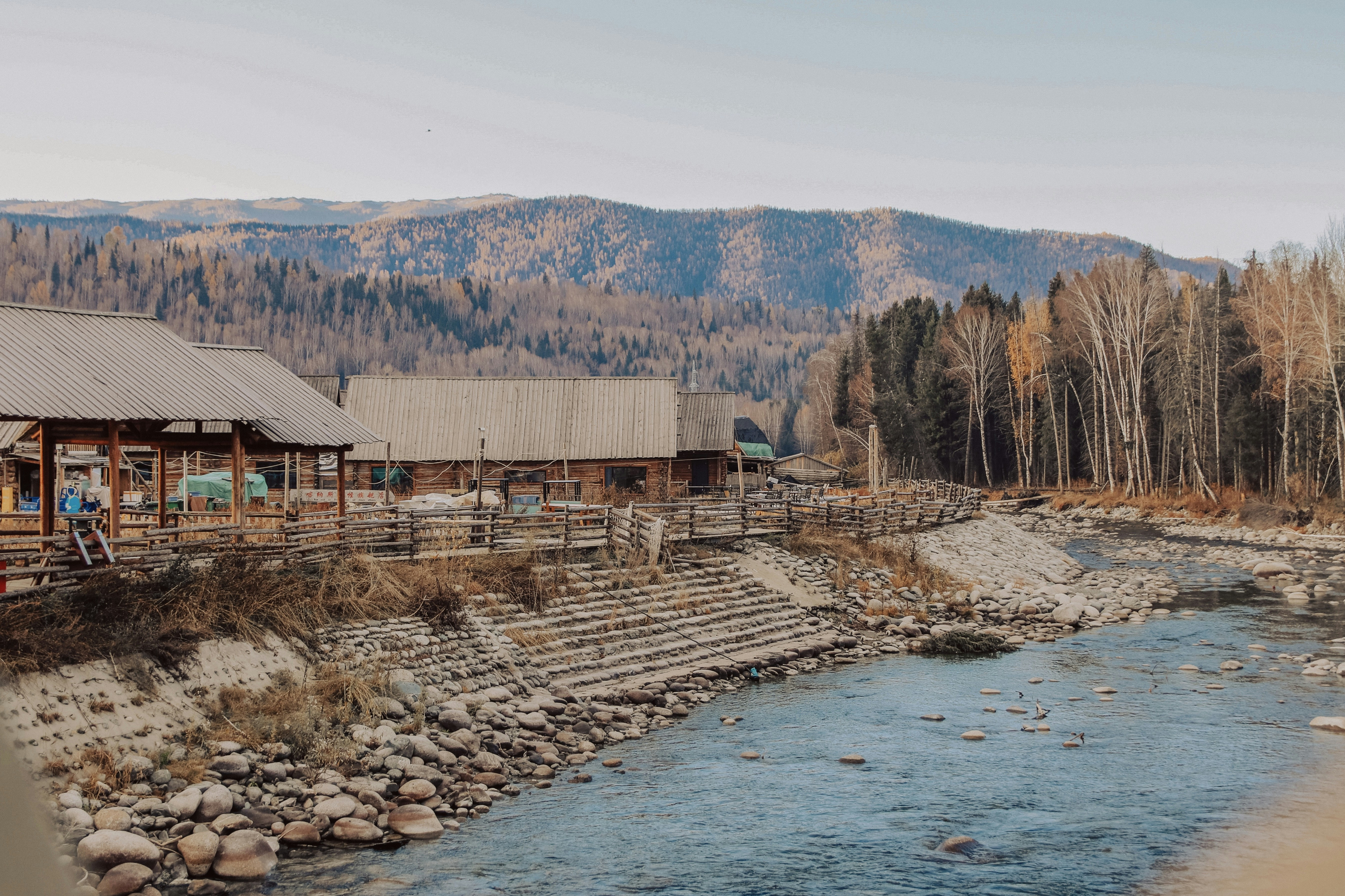 Ein malerischer Fluss fließt an Hütten und Bergen vorbei.