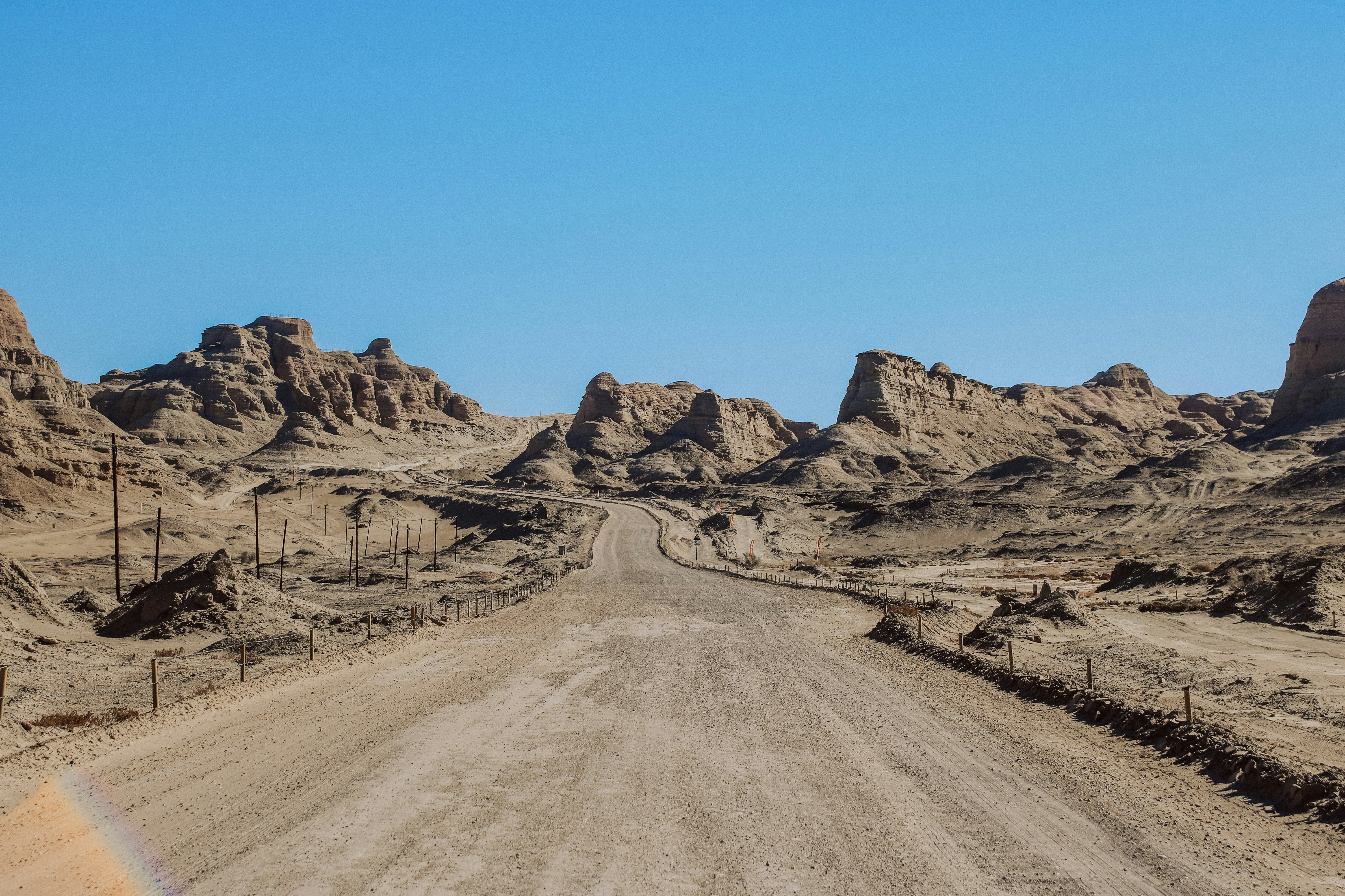 Eine staubige Straße führt durch eine Wüstenlandschaft.