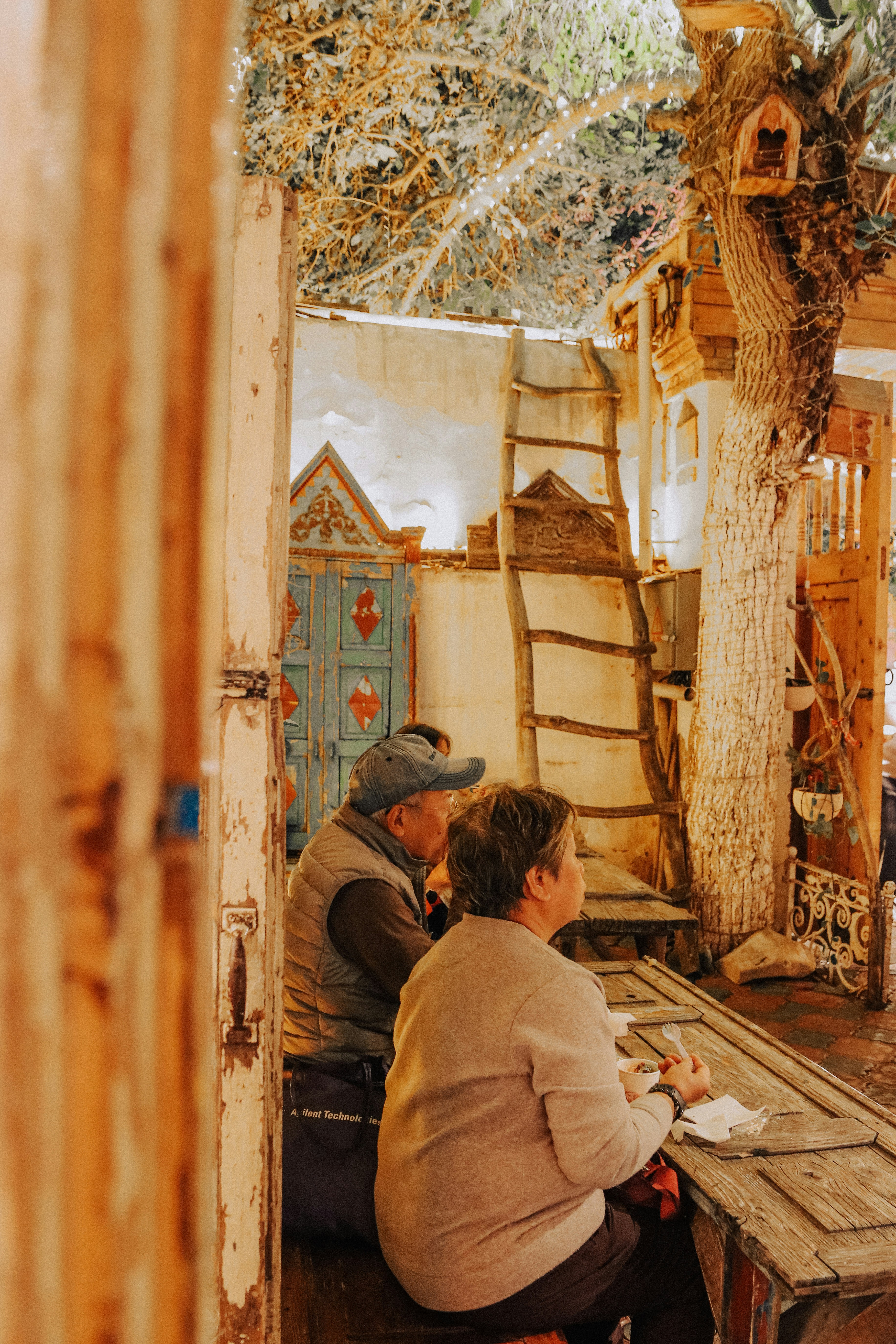 Zwei Personen sitzen an einem Tisch vor einem Café.
