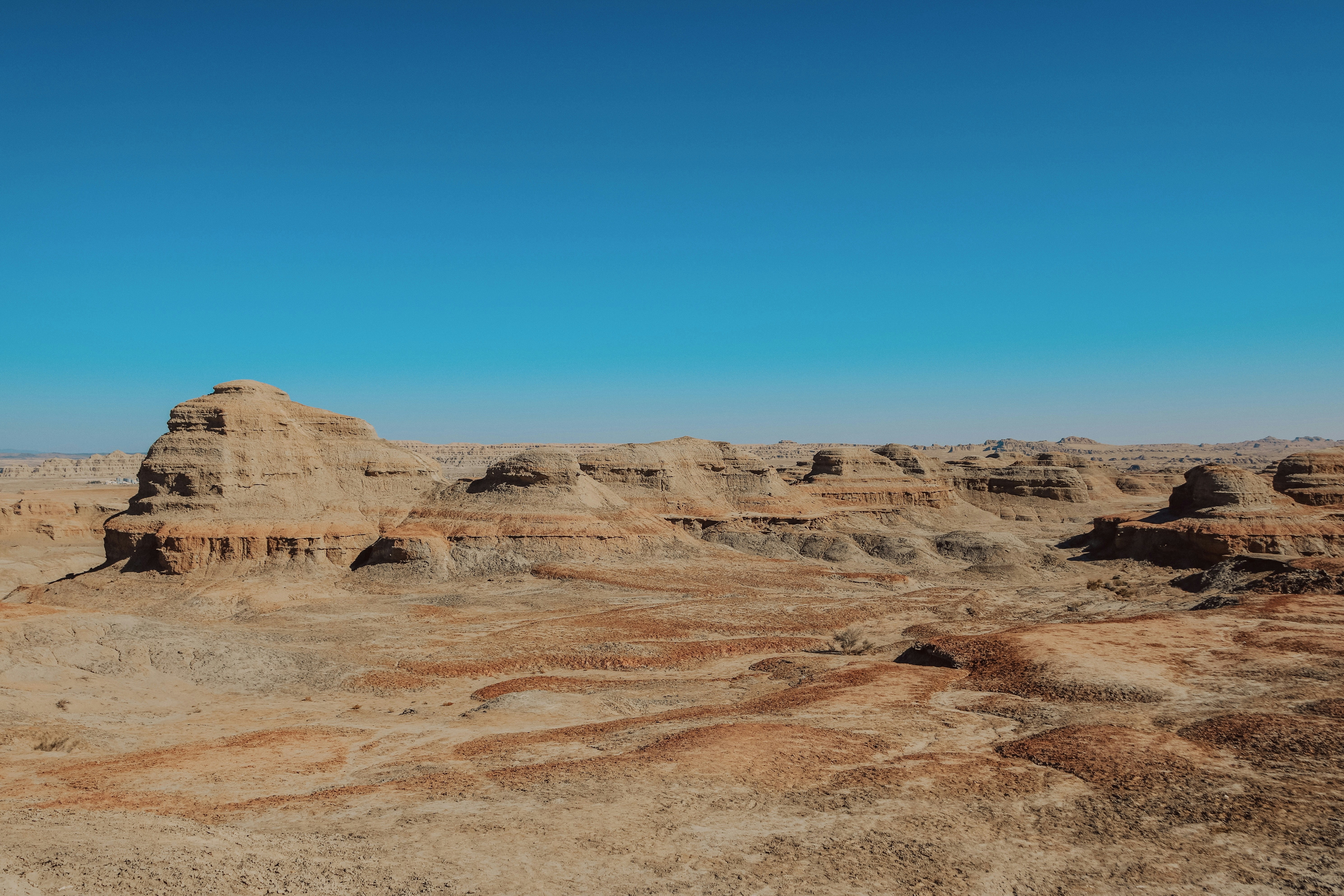 Wüstenlandschaft mit Felsformationen unter blauem Himmel.
