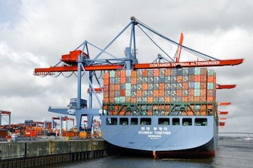 A cargo ship is being loaded at a port.