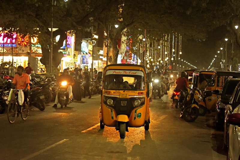 Yellow rickshaw navigating a busy Indian street at night