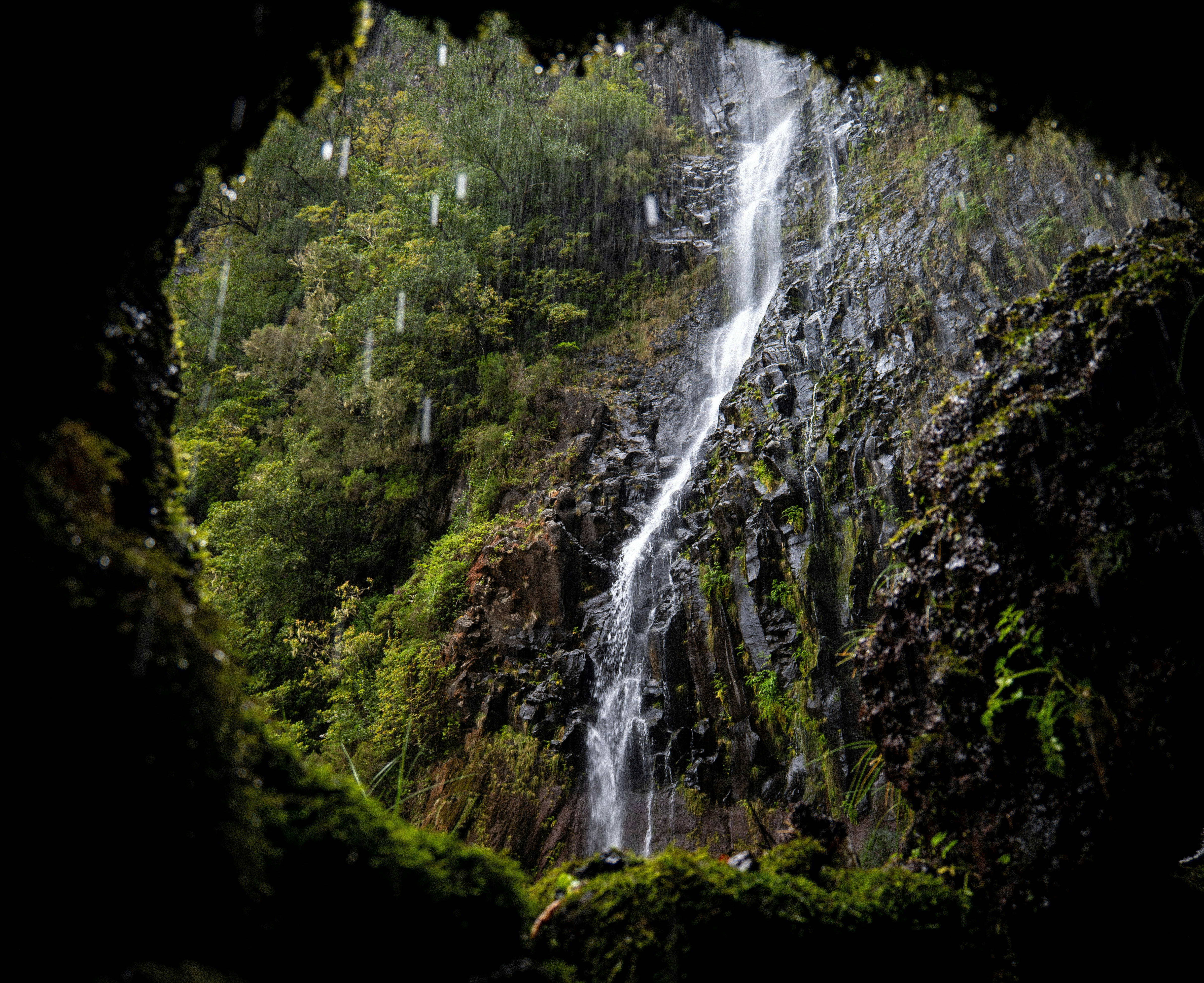 Waterfall seen through a dark cave opening.