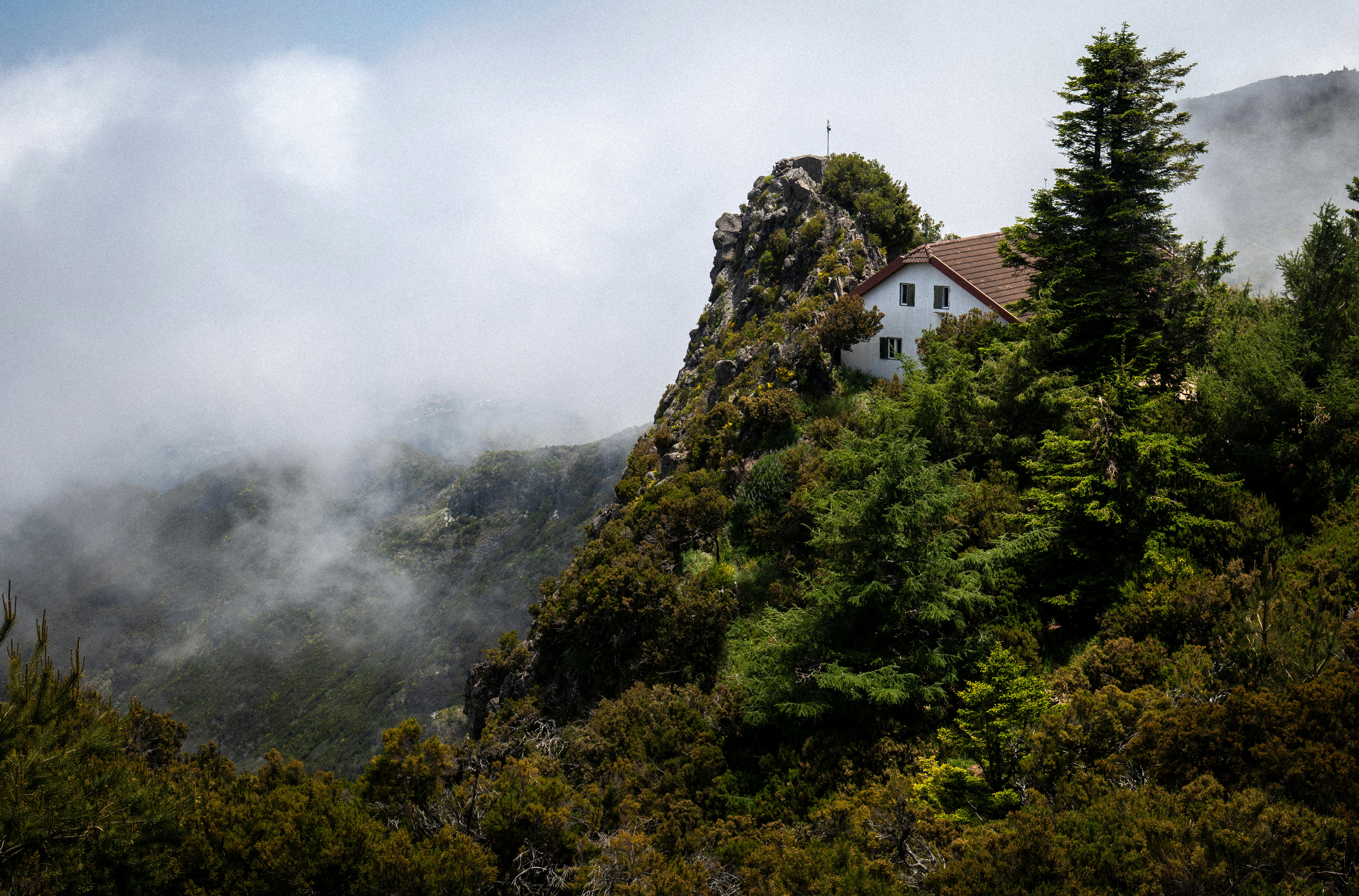 A house sits on a cliff, surrounded by clouds.