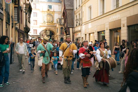 People in costumes parade down a european street.