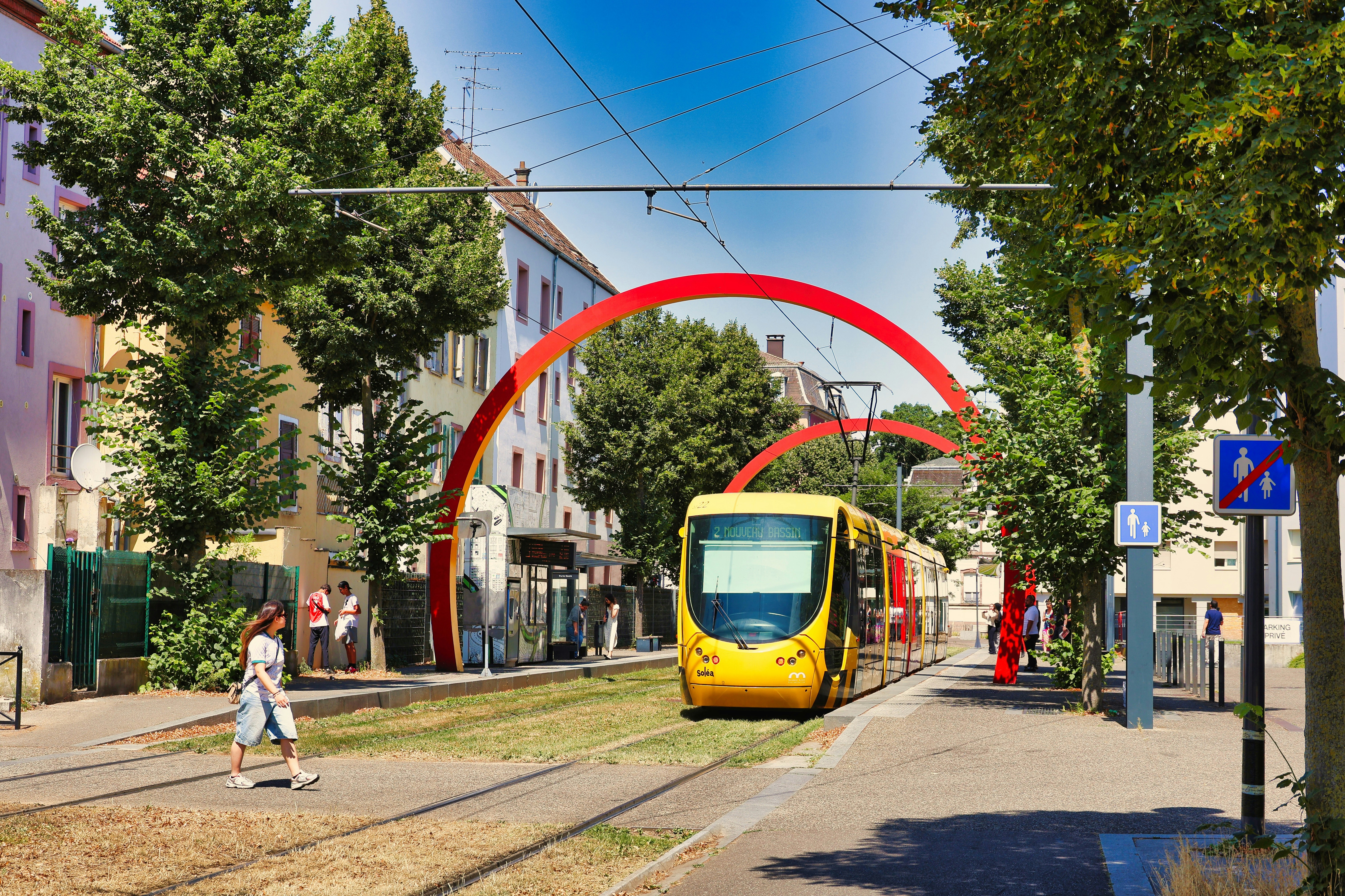 A yellow tram runs on tracks in a city.