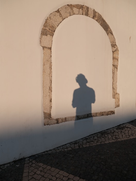 A shadow stands within the stone arch.
