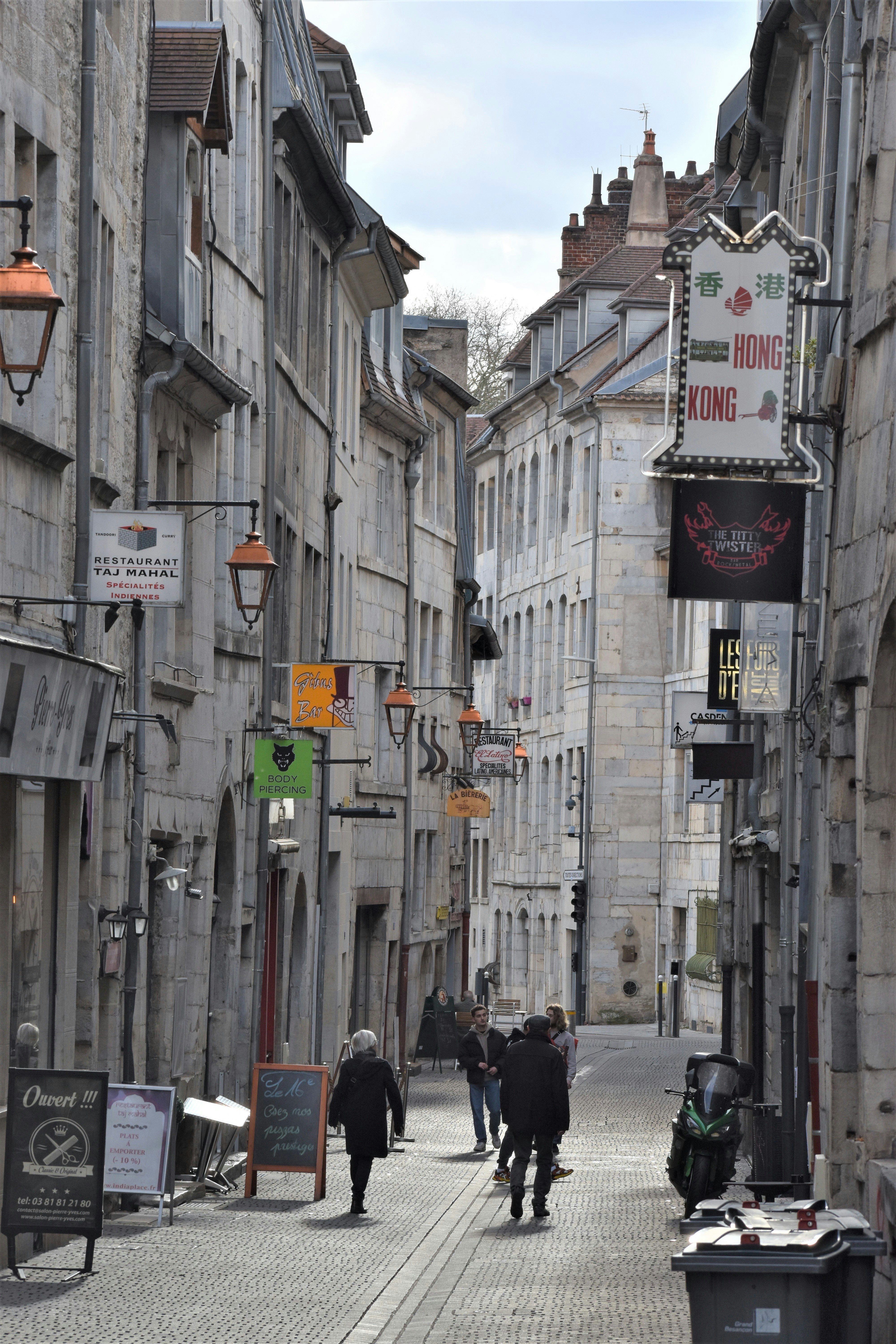 Narrow street with buildings and people walking.