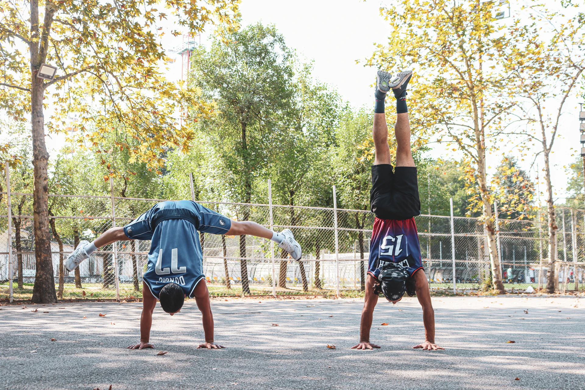 Two people practice handstands outdoors.