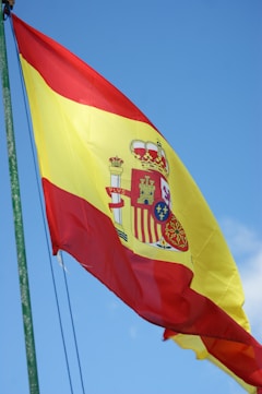 The spanish flag flutters against a blue sky.