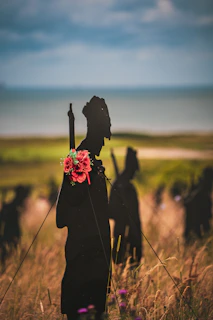 Silhouette soldiers with flowers stand at the shore.
