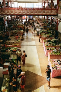 People shop at an indoor market with many stalls.