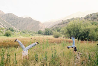 Two people are doing cartwheels in a field.