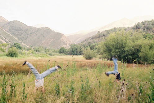 Two people are doing cartwheels in a field.