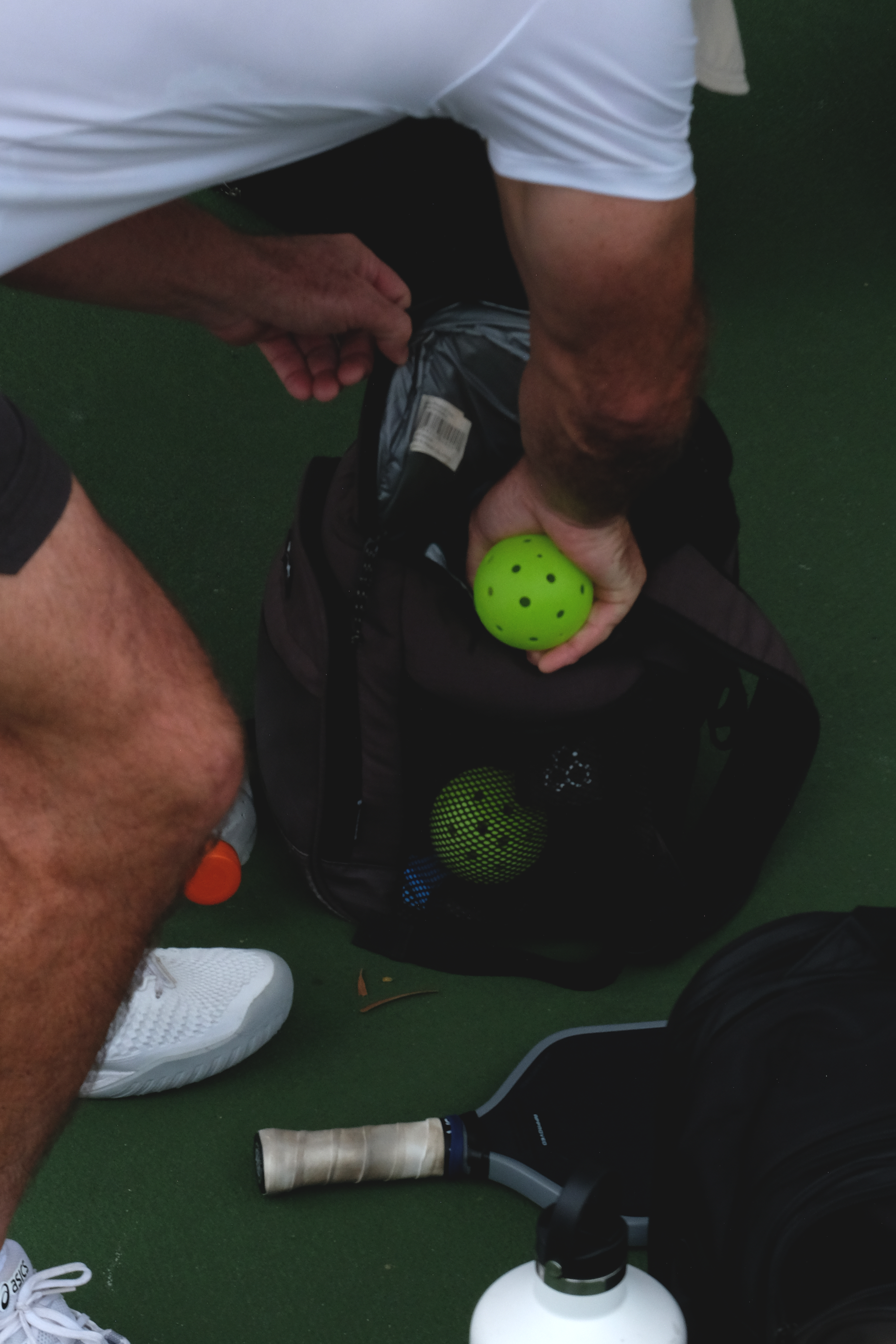 A person is taking pickleballs from a bag.
