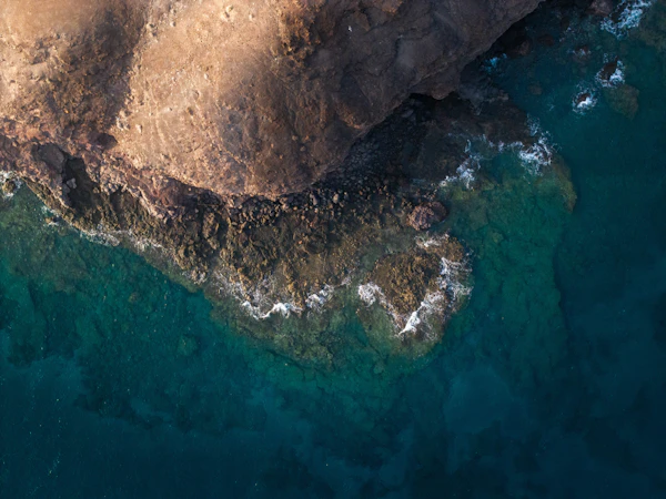Costa rocosa volcánica encontrándose con el mar azul profundo