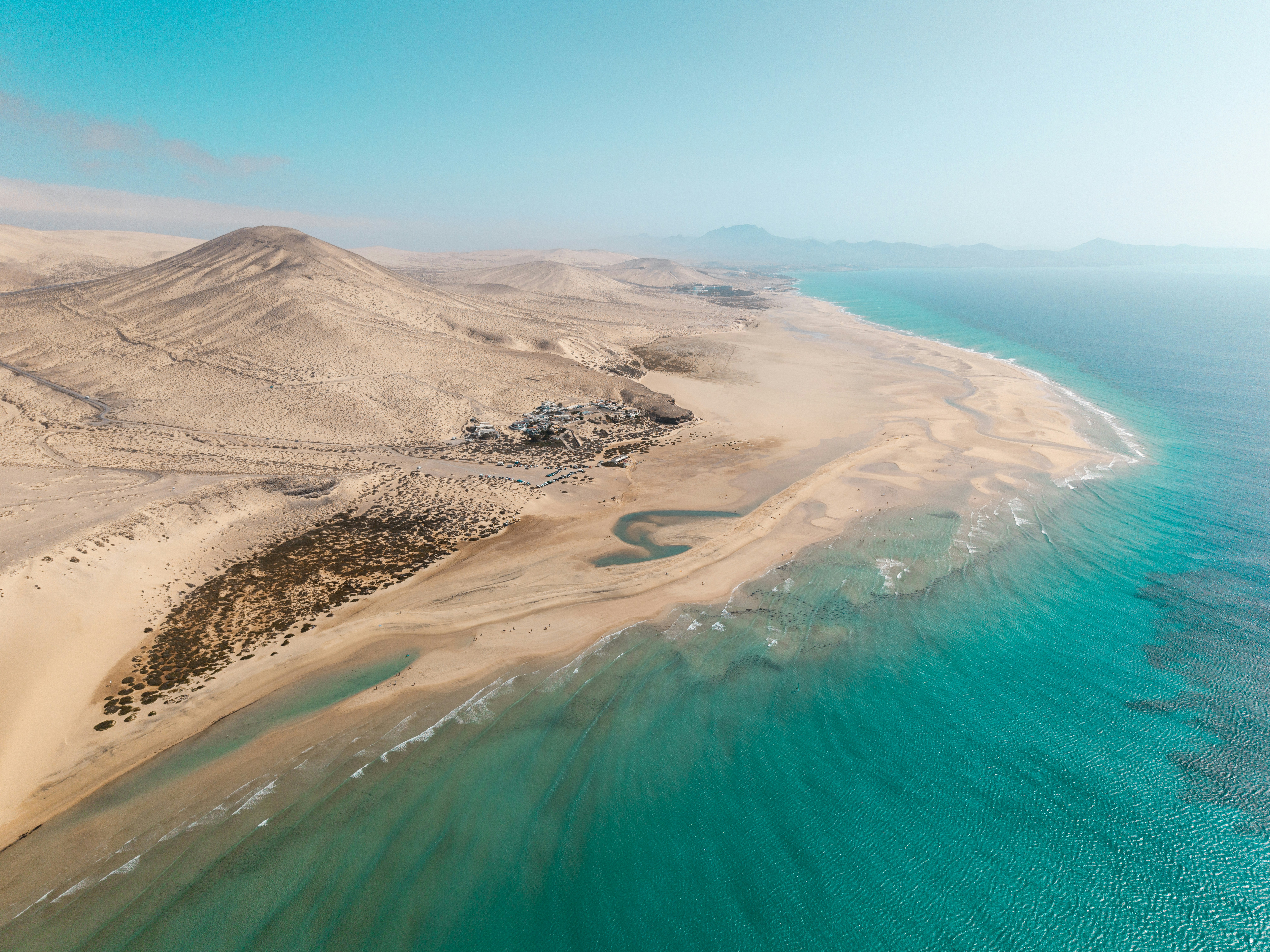 Sandy coastline meets turquoise water under a bright sky.