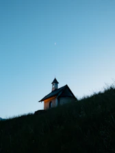 A chapel sits atop a grassy hill at dusk
