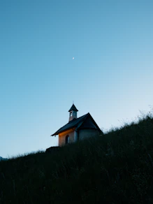 A chapel sits atop a grassy hill at dusk