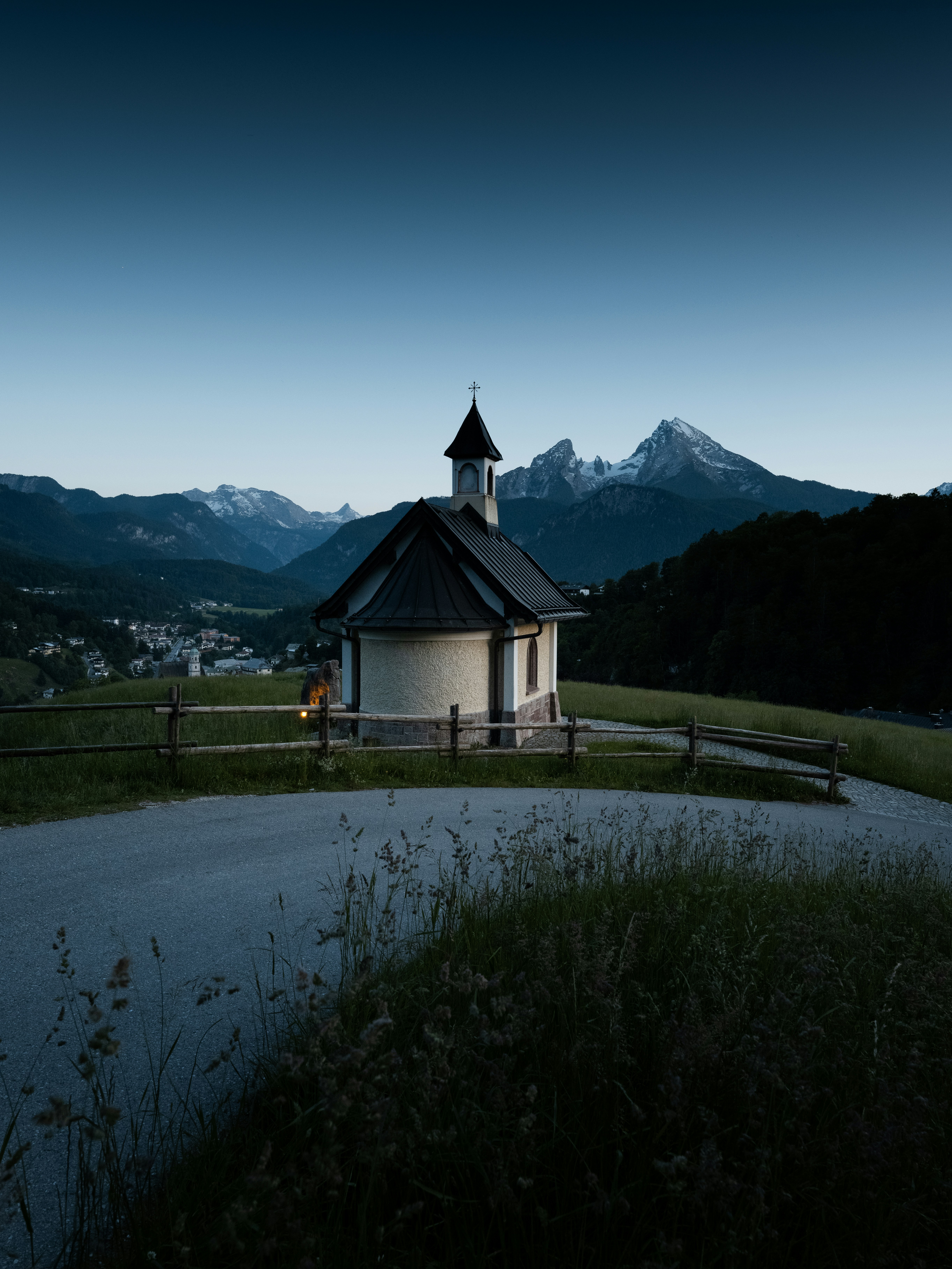 A tiny church rests near mountains at dusk.