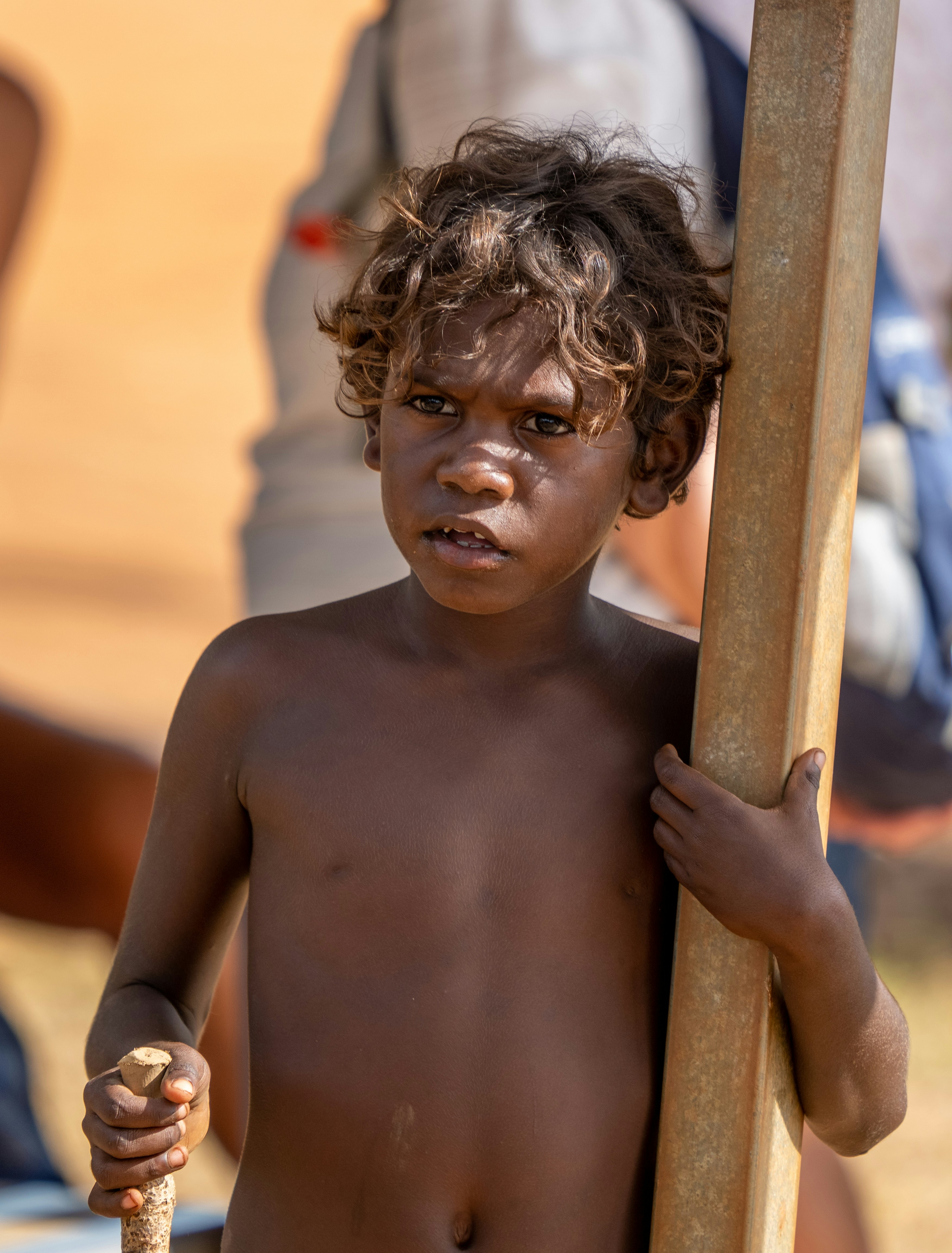 Ein junger Aborigine-Junge hält einen Holzpfahl in der Hand.