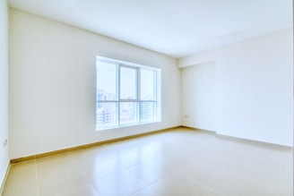 An empty, bright room with a large window.