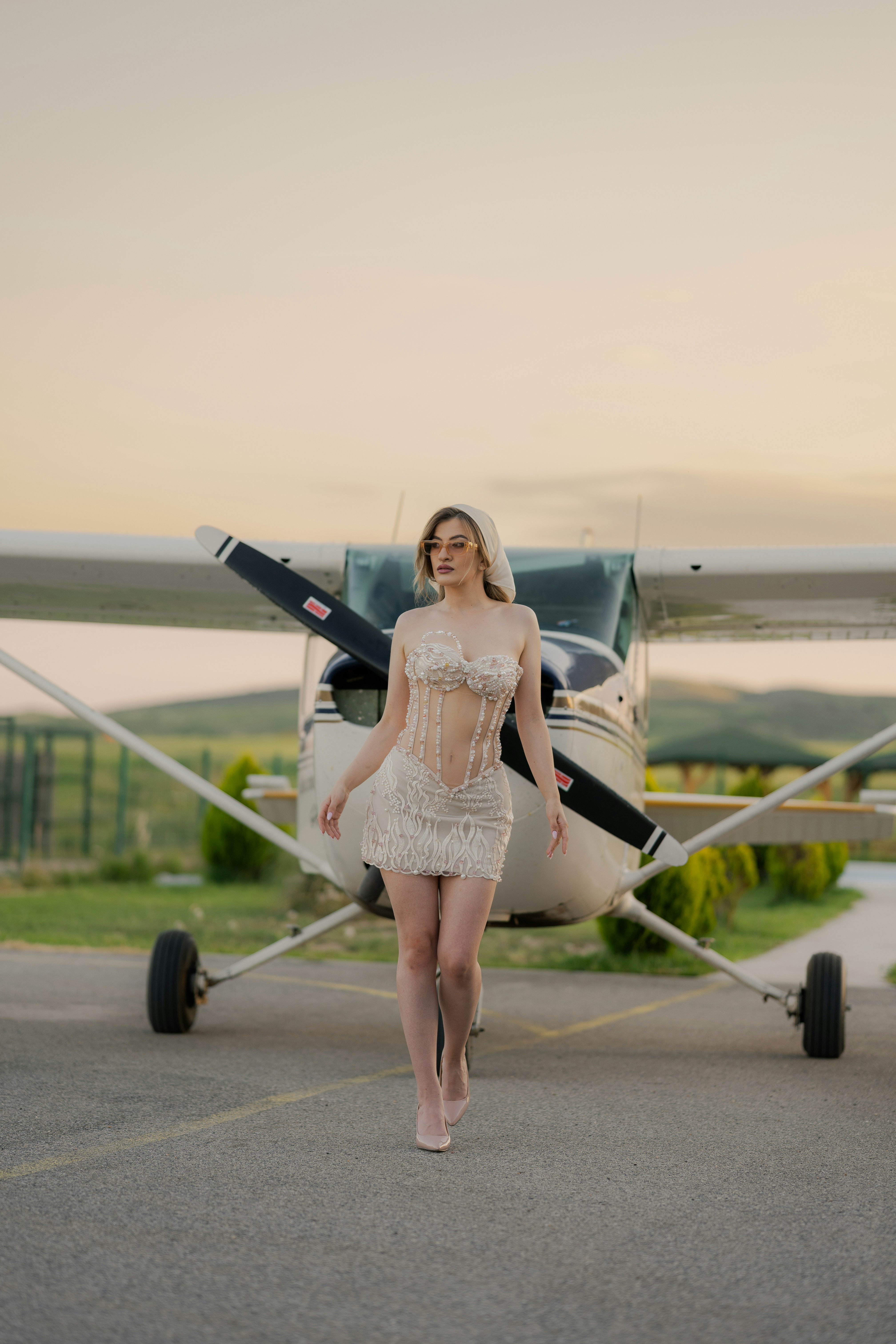 Woman poses in front of a small airplane.