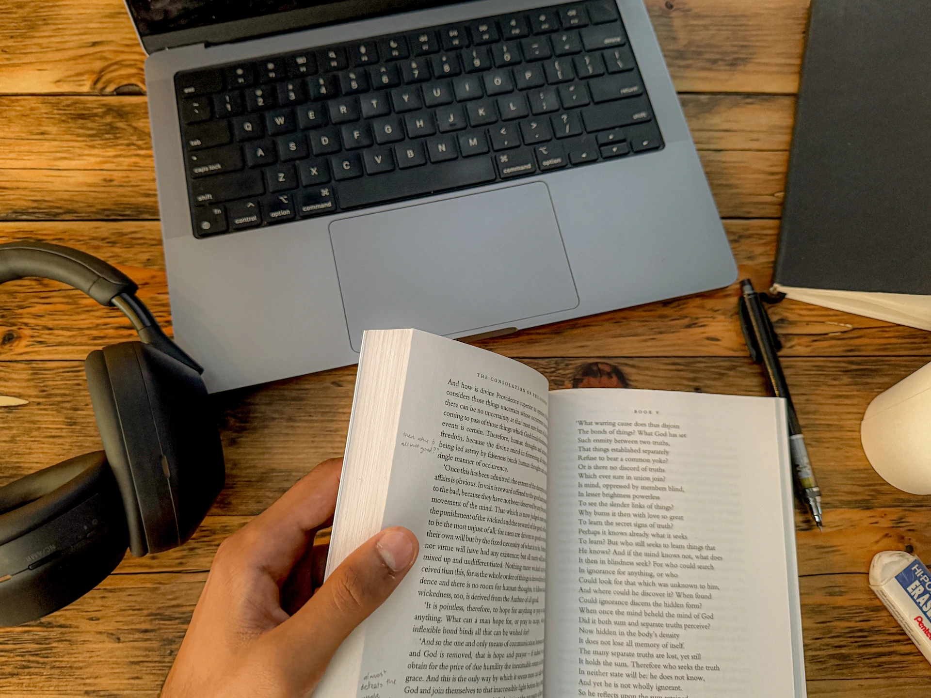 A person reads a book at a workspace.