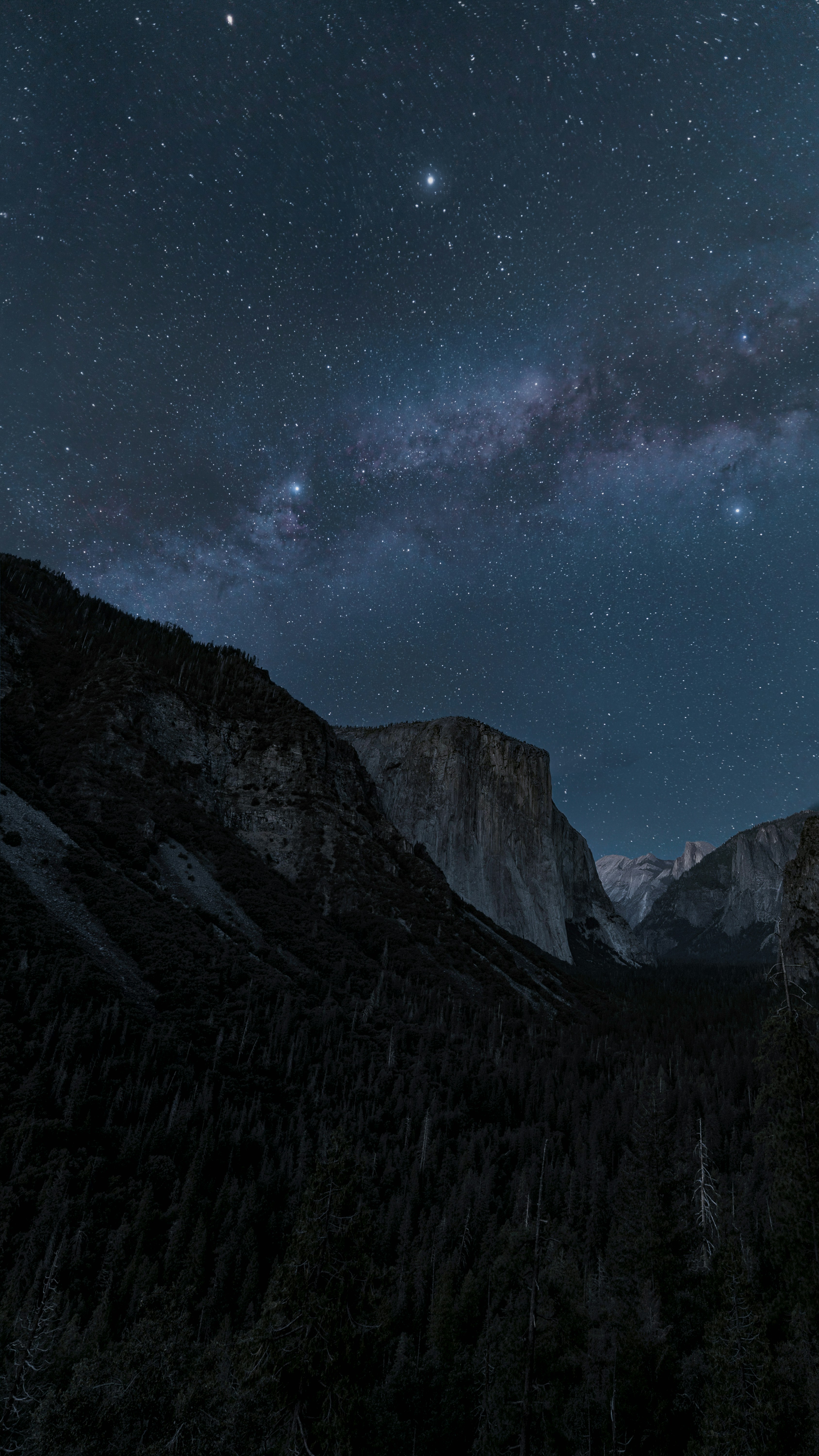 Milky way over mountains and forests at night.