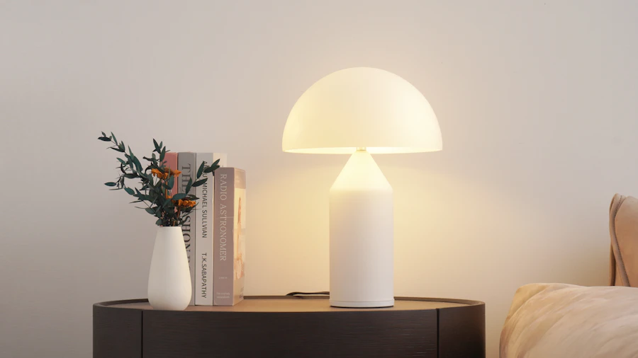 A glowing lamp beside a vase and books