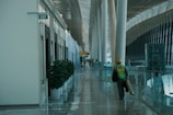 A worker walks down a brightly lit airport hallway.