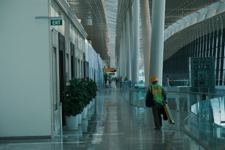 A worker walks down a brightly lit airport hallway.