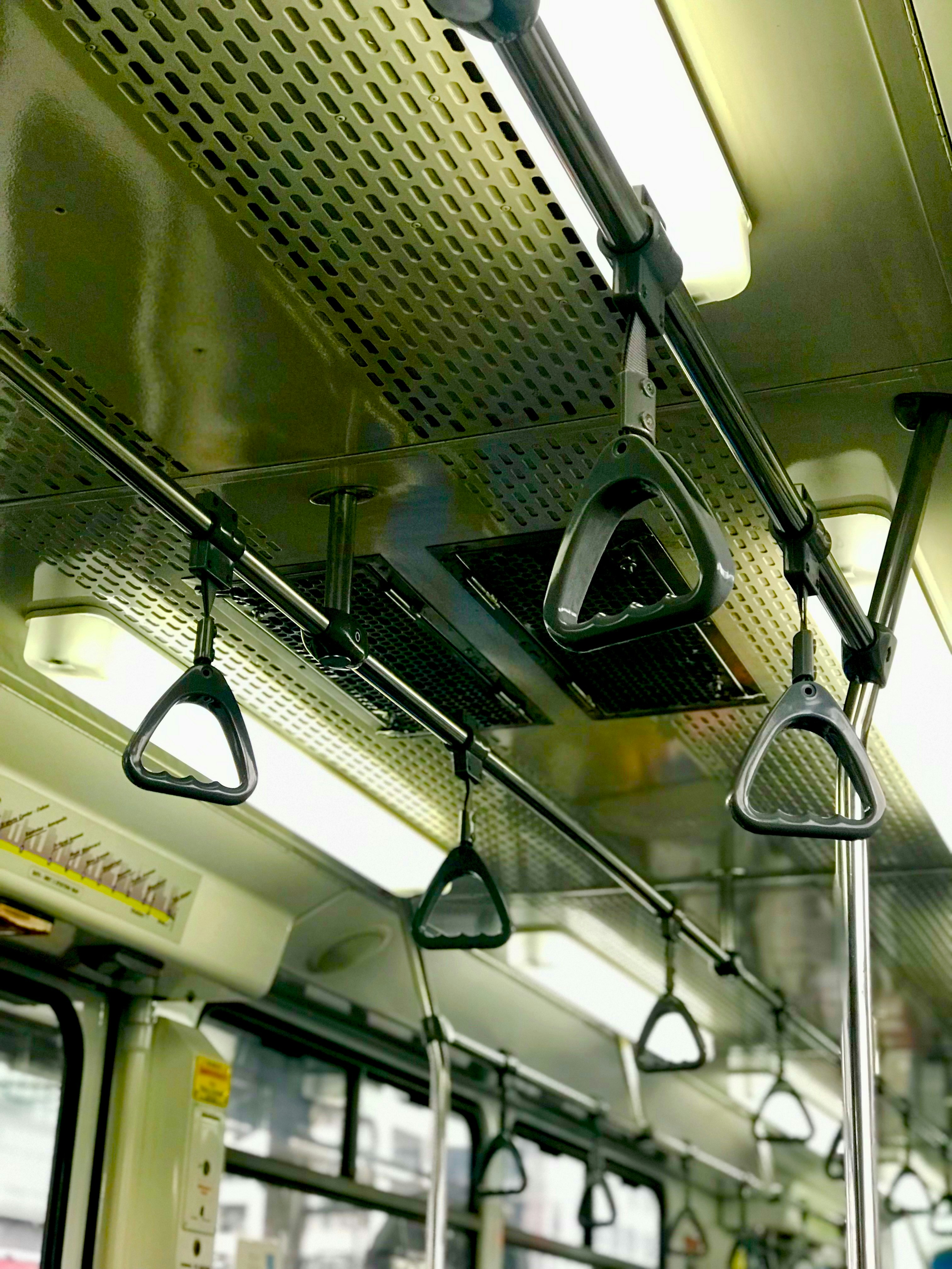 Inside a subway car with hanging handholds.