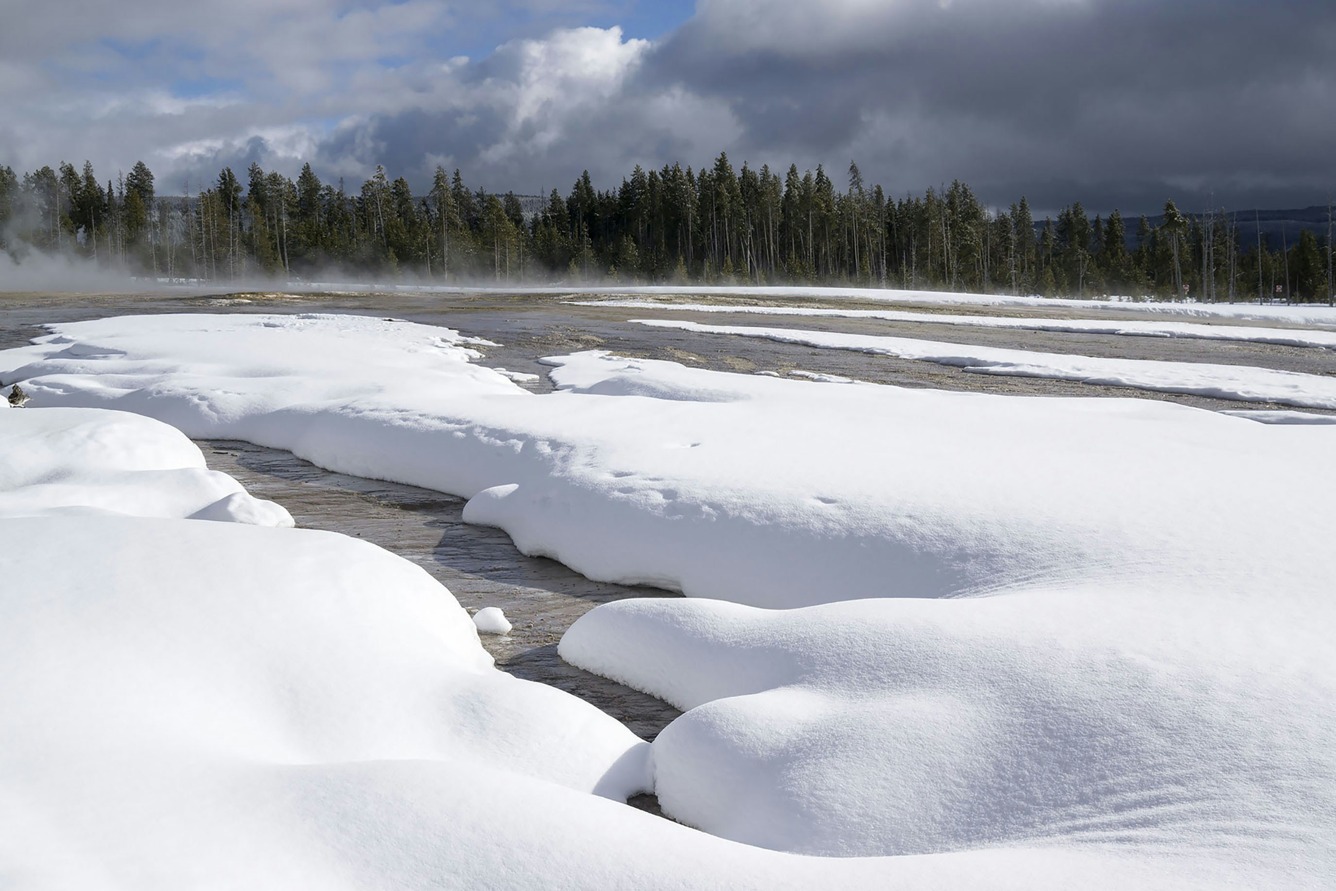 Snowy landscape with steam rising from the water.