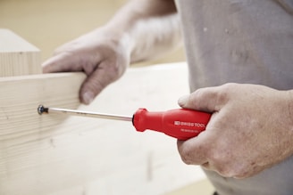 A person uses a screwdriver on wood.