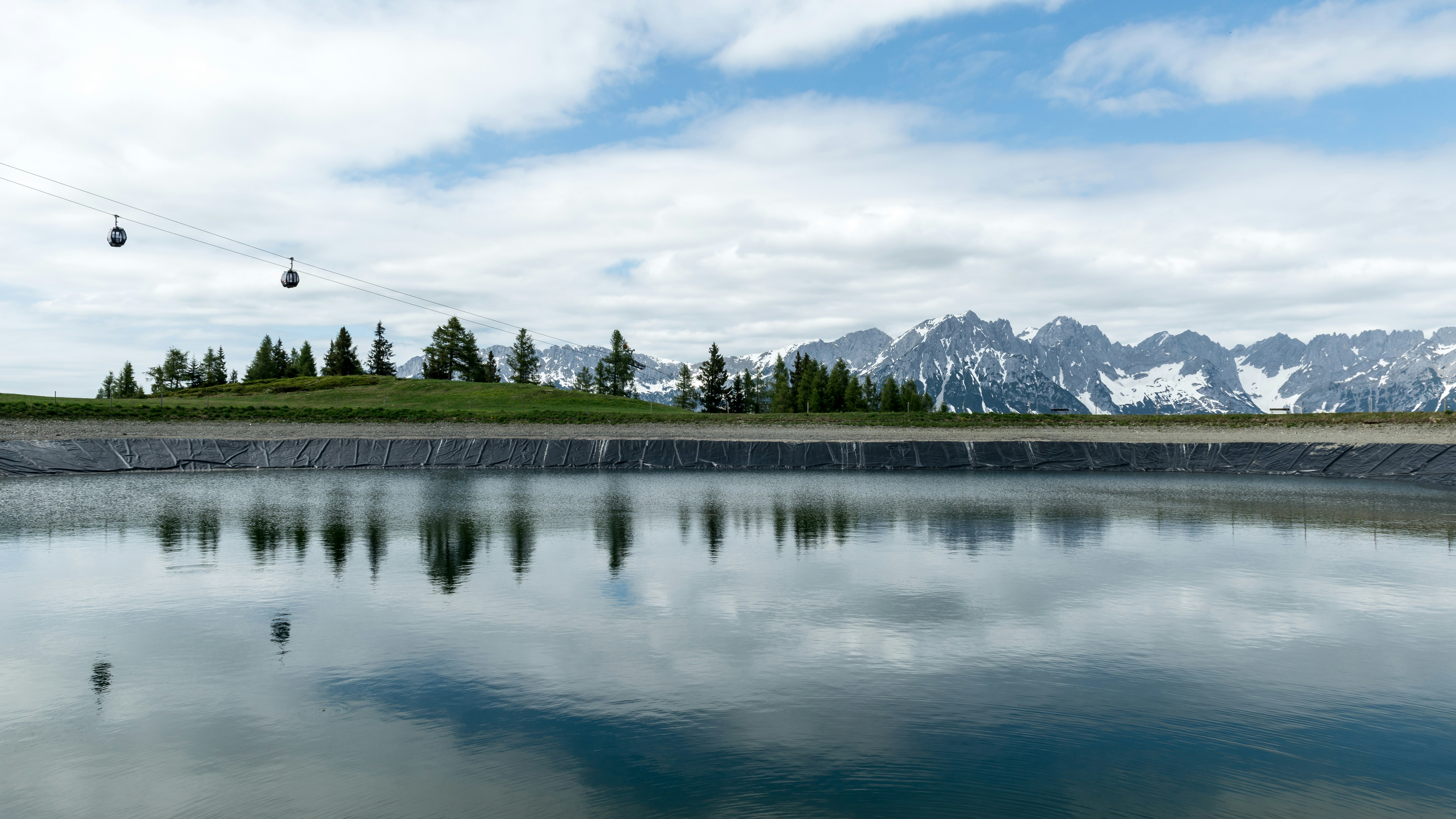 A lake reflects the clouds and mountains.