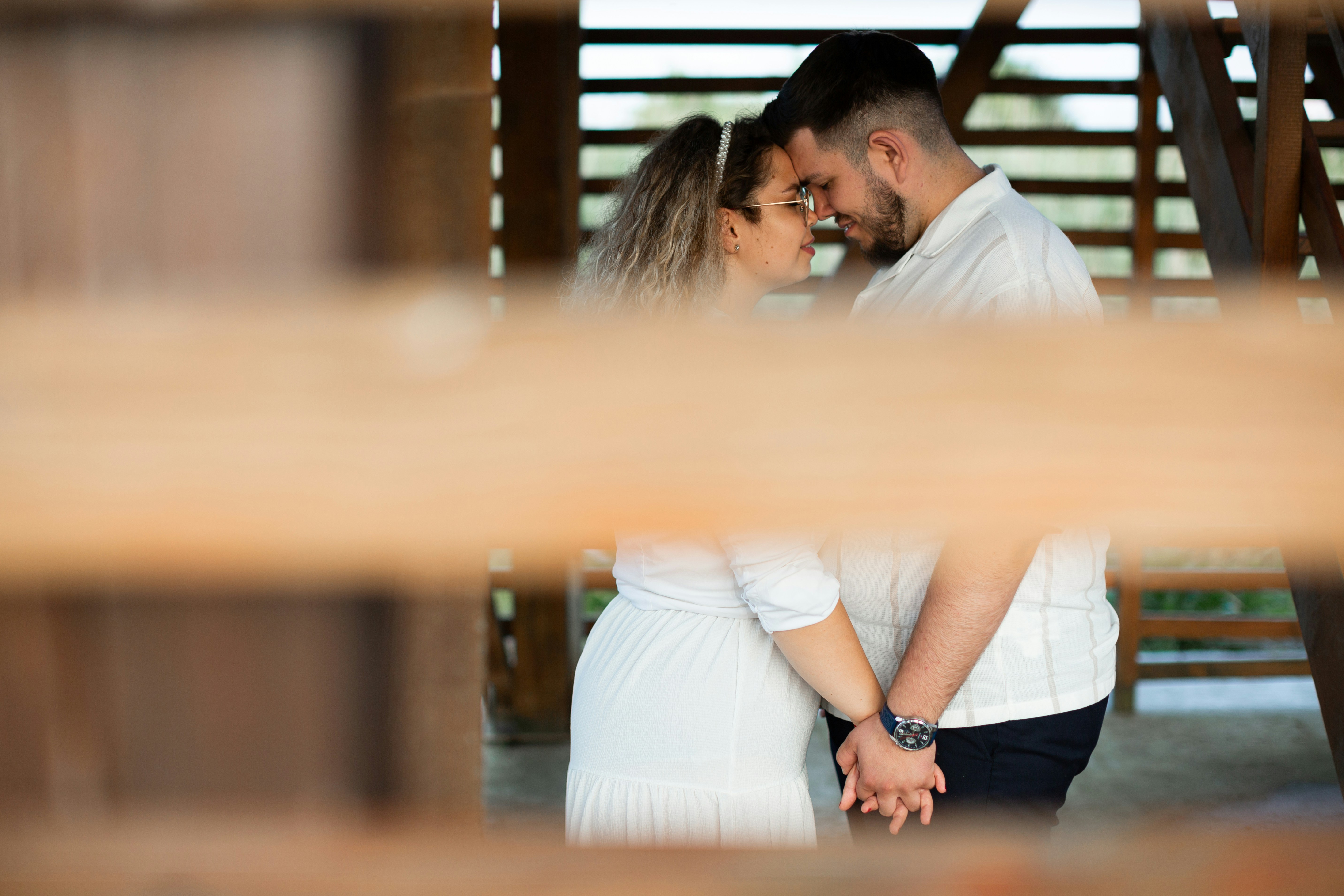 A loving couple embraces inside a wooden structure.
