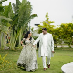A newlywed couple strolls through a lush garden.