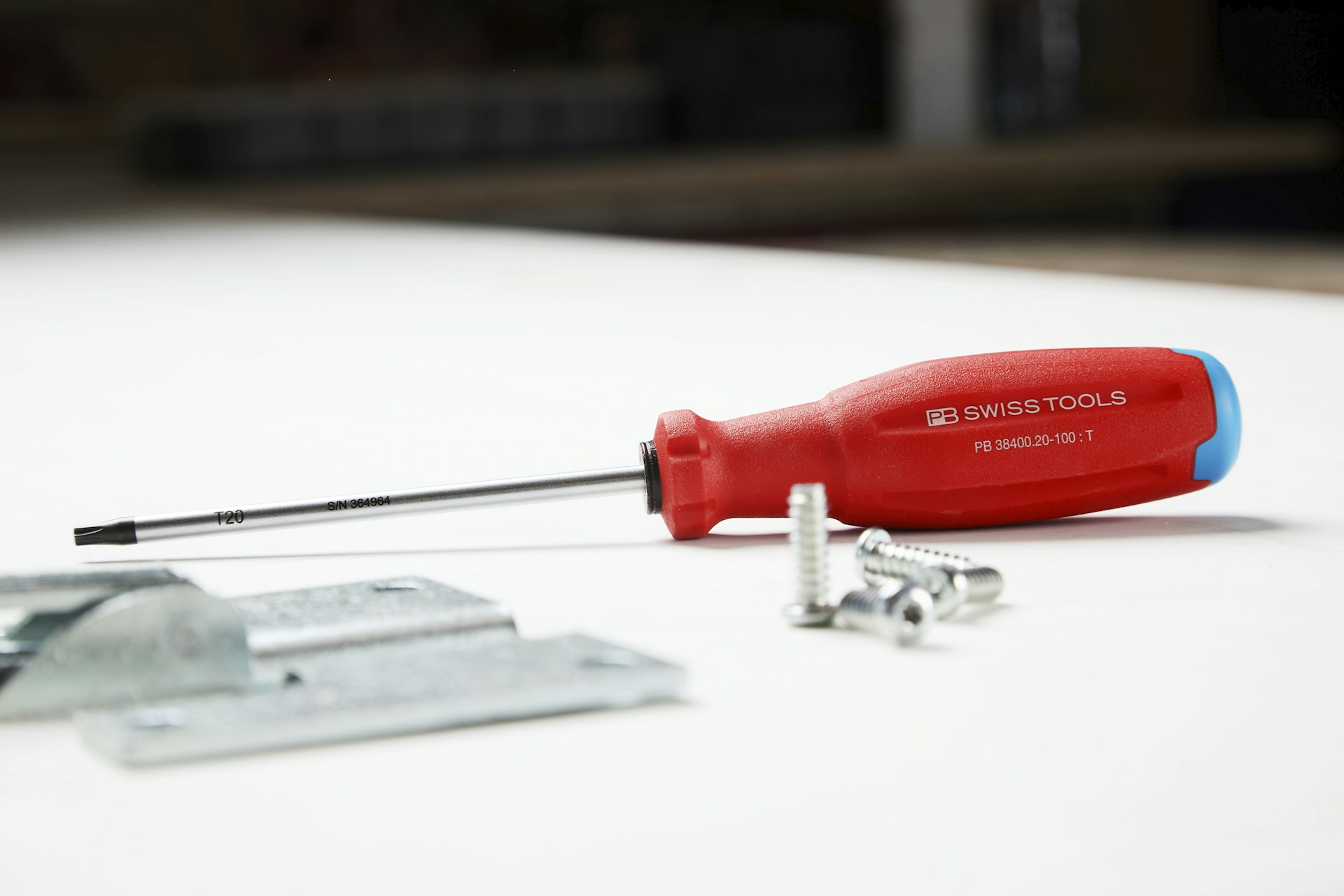 A screwdriver and some hardware are on a surface.