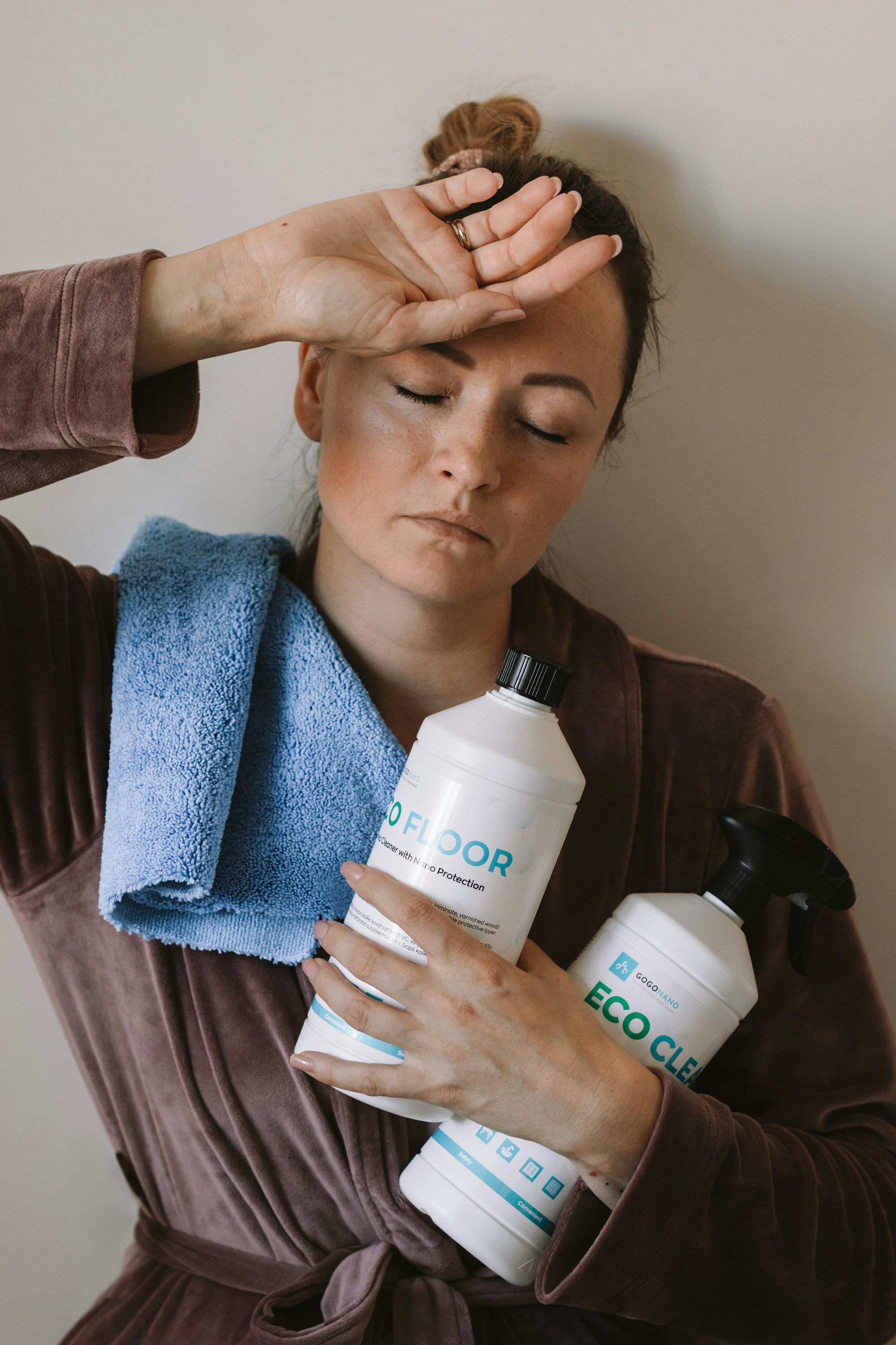 Exhausted woman holds cleaning supplies after work.