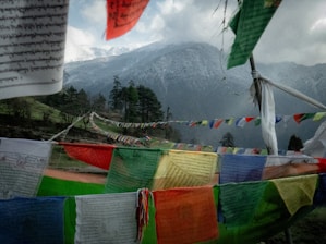 Prayer flags flutter before a mountainous backdrop.