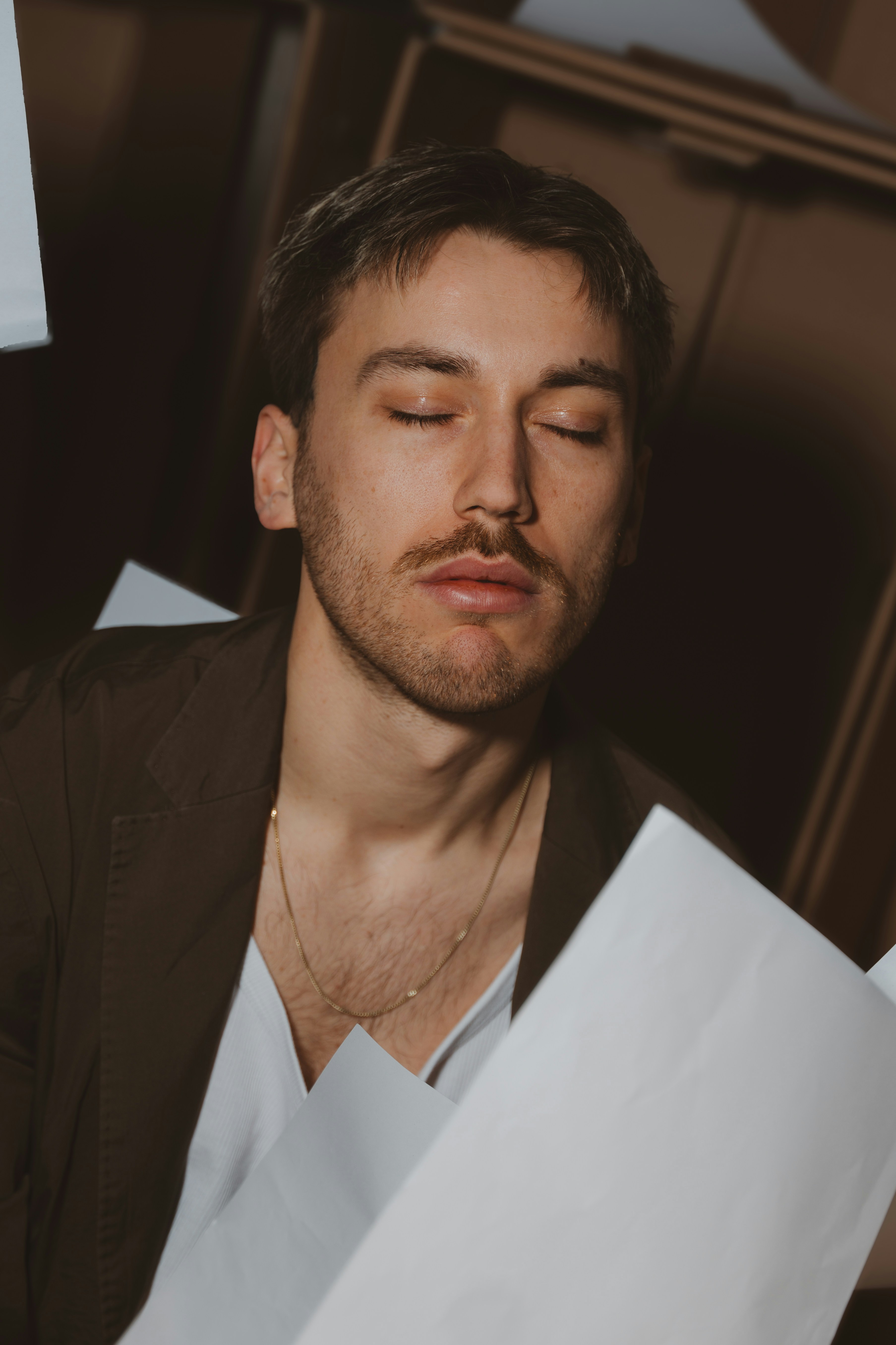 Man with eyes closed surrounded by falling papers.