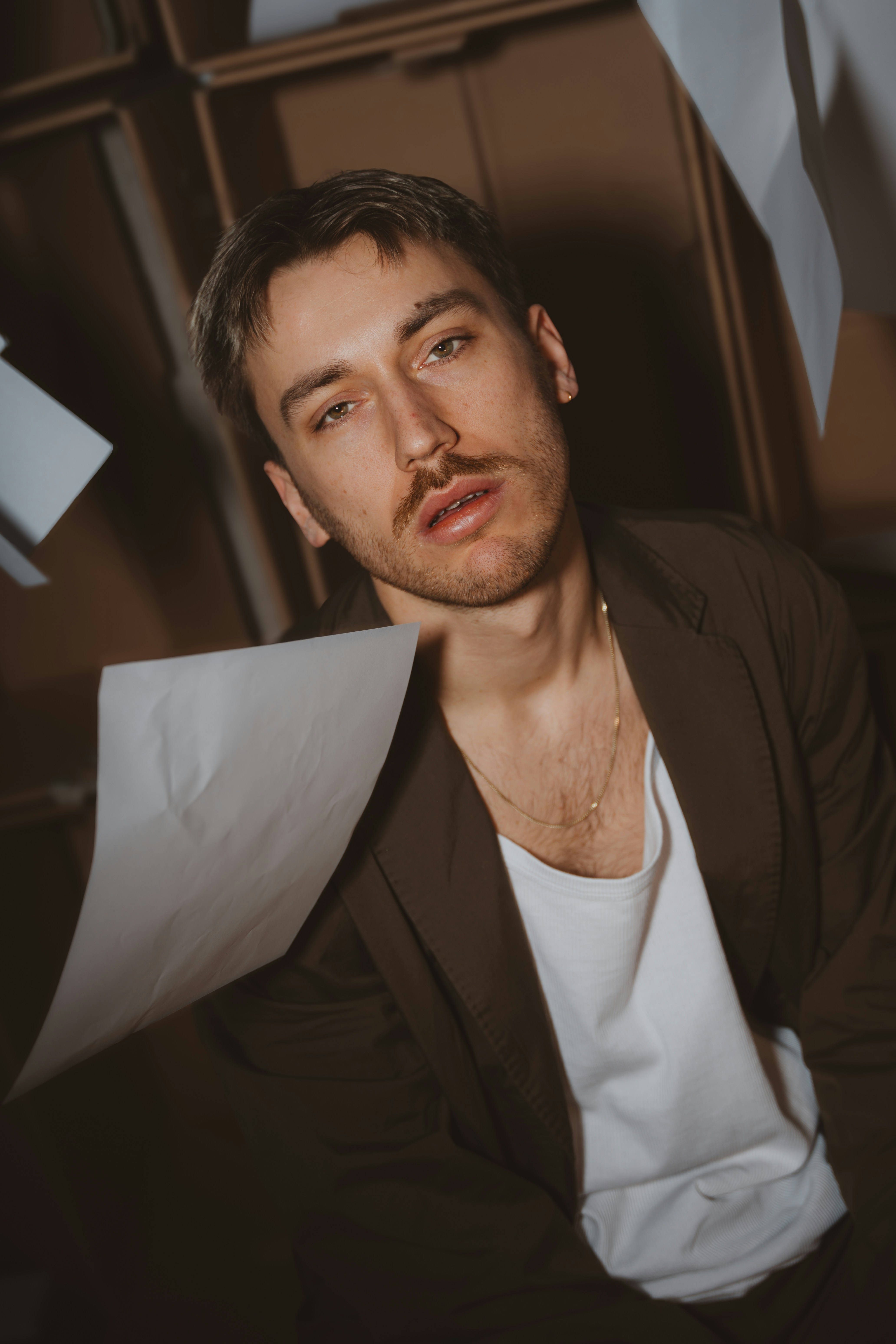 Man is surrounded by falling papers in a room.