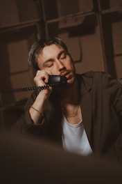 Man leans on the phone, appearing sleepy.