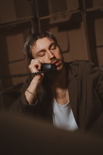 Man leans on the phone, appearing sleepy.
