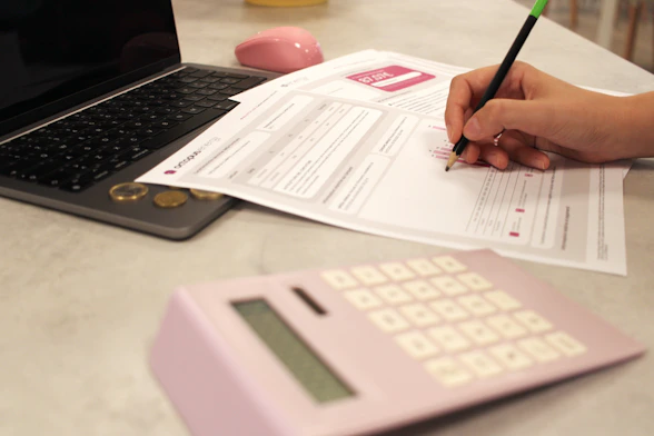 Someone is working on paperwork with a calculator.