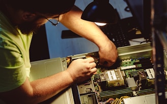 Man repairing a computer server under a lamp.